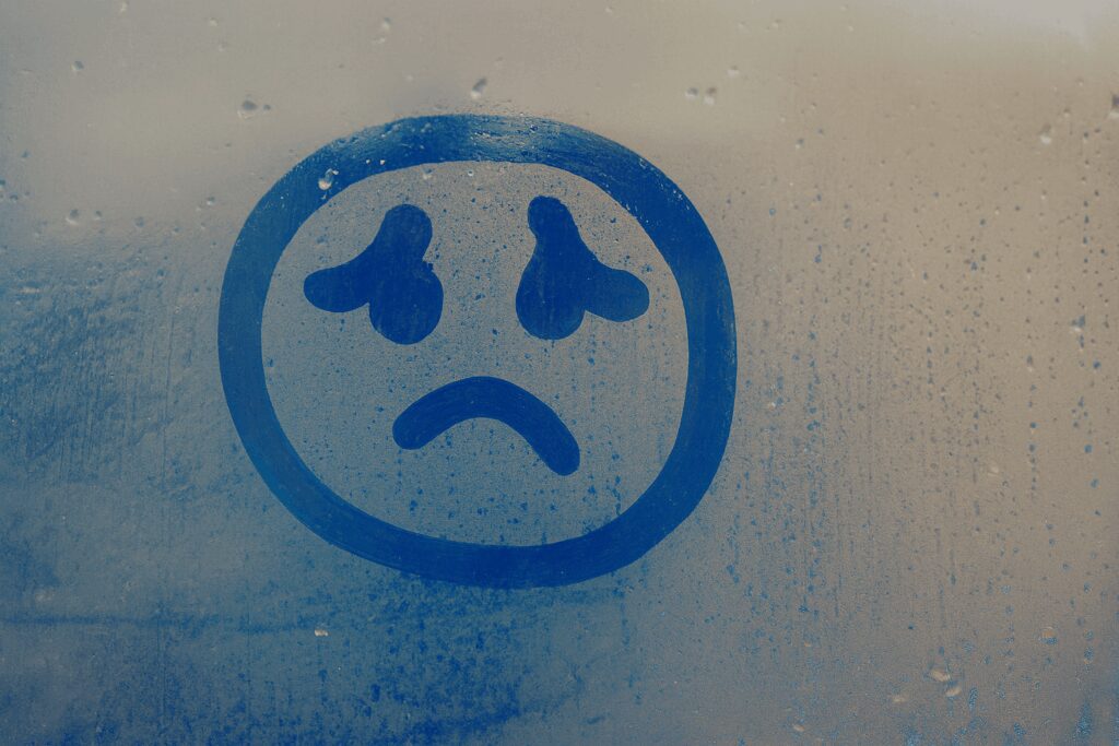 Carinha triste desenhada em vidro embaçado