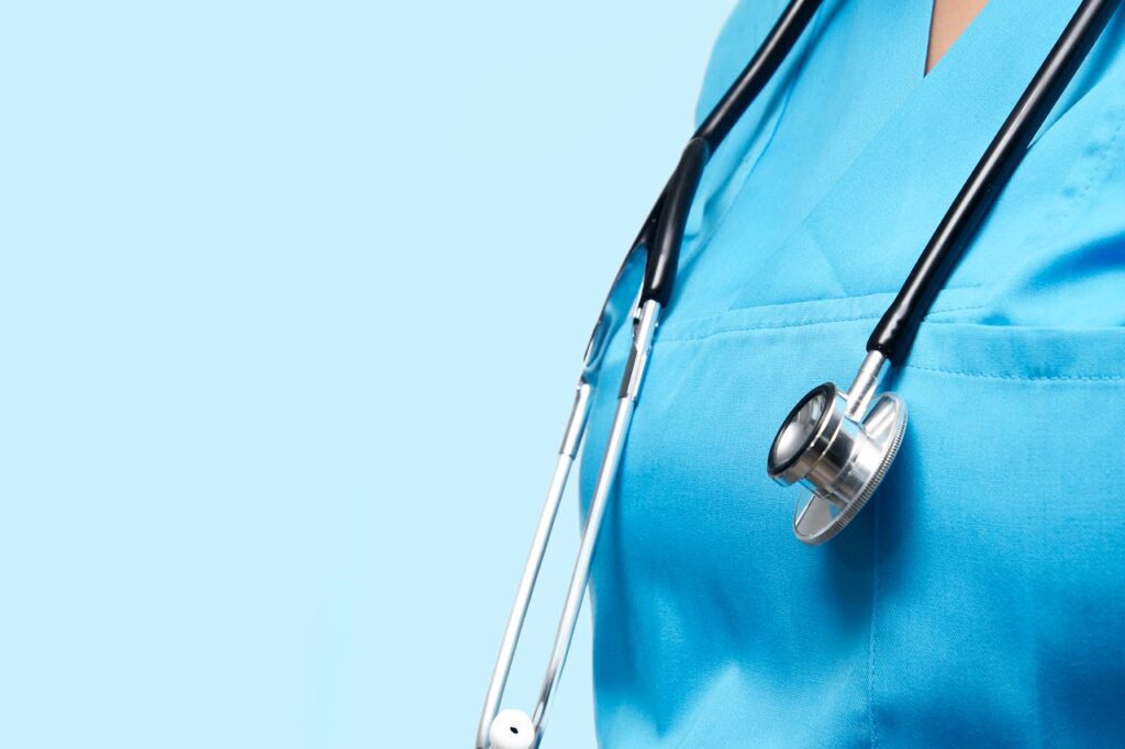 Profissional de saúde vestindo uniforme azul com estetoscópio pendurado no pescoço, em fundo azul claro