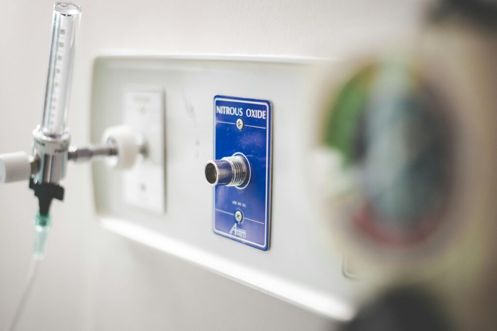  Saída de óxido nitroso instalada em parede de consultório médico, com válvula e medidor de fluxo visíveis. A imagem destaca a infraestrutura clínica voltada para sedação consciente com segurança.